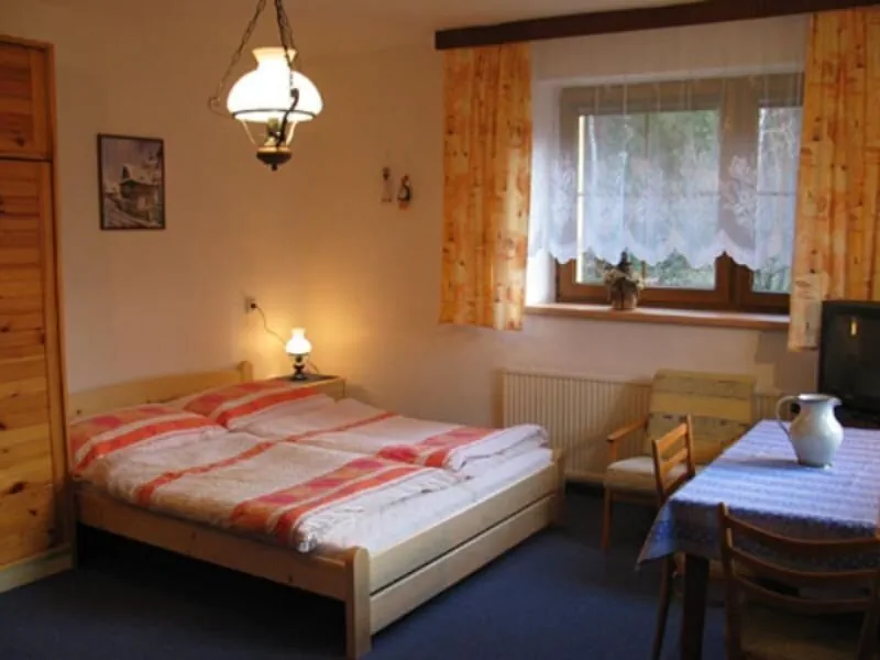 Třílůžkový pokoj s postelí, lampou a dřevěným nábytkem